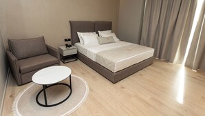 Une chambre d’hôtel moderne équipée d’un lit, d’un canapé, d’une petite table et d’une table de chevet.