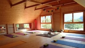 Ein Yoga-Studio mit Holzwänden, großen Fenstern und Yogamatten.