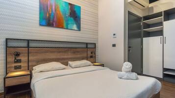 A modern hotel room with a large bed, a wardrobe, and a colorful abstract painting on the wall.