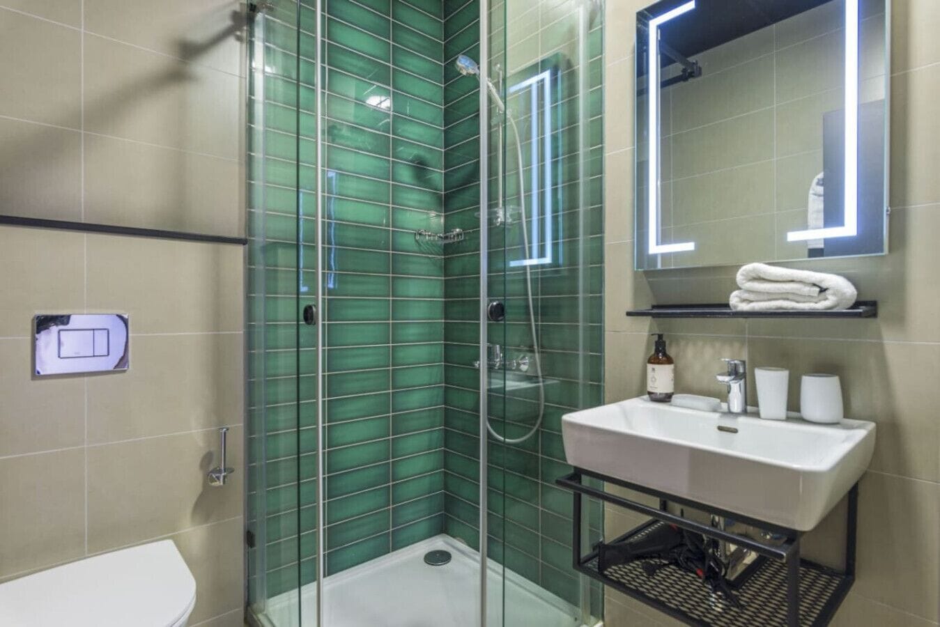 A modern bathroom with a glass-enclosed shower, a white sink, and a mirror with a lighted frame.