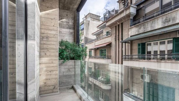 A narrow balcony with a glass railing, a concrete wall, and a small patch of greenery. - Amine Apart-Hotel by Stayinn (Beirut)