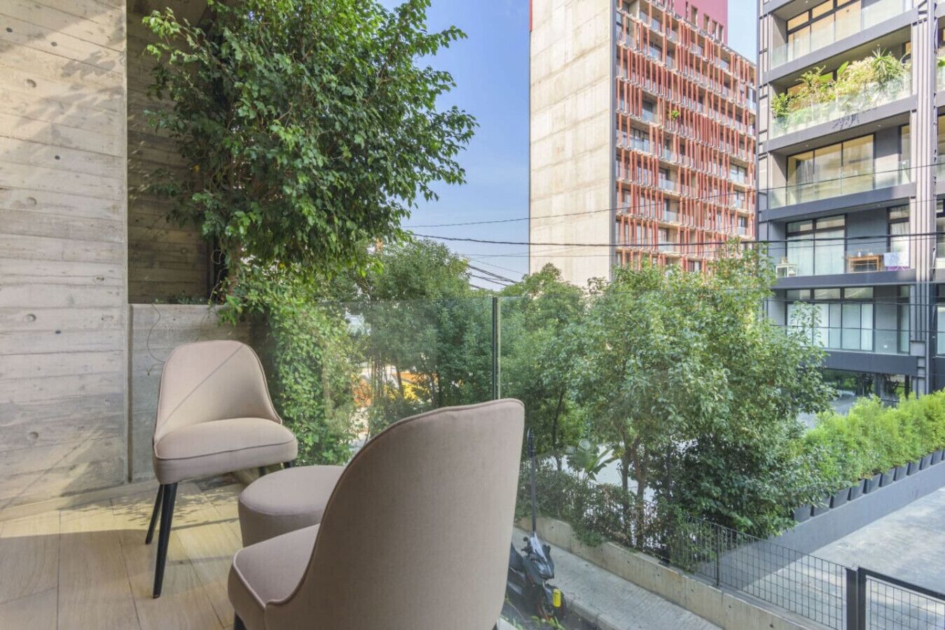 Un balcon avec deux chaises, une vue sur un immeuble doté de balcons et un arbre.