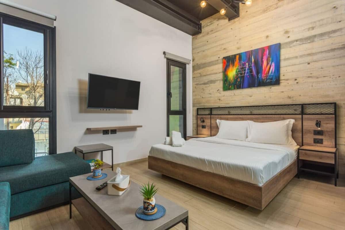 Una habitación de hotel moderna con una cama grande, un televisor, un sofá y una mesita de centro.