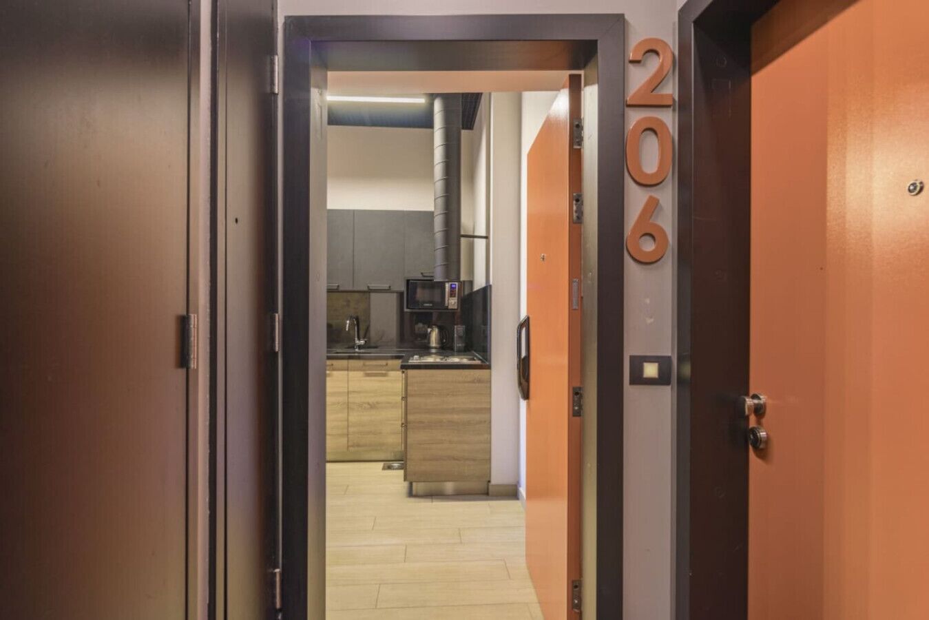 A hallway leading to a kitchen with a microwave, sink, and cabinets.