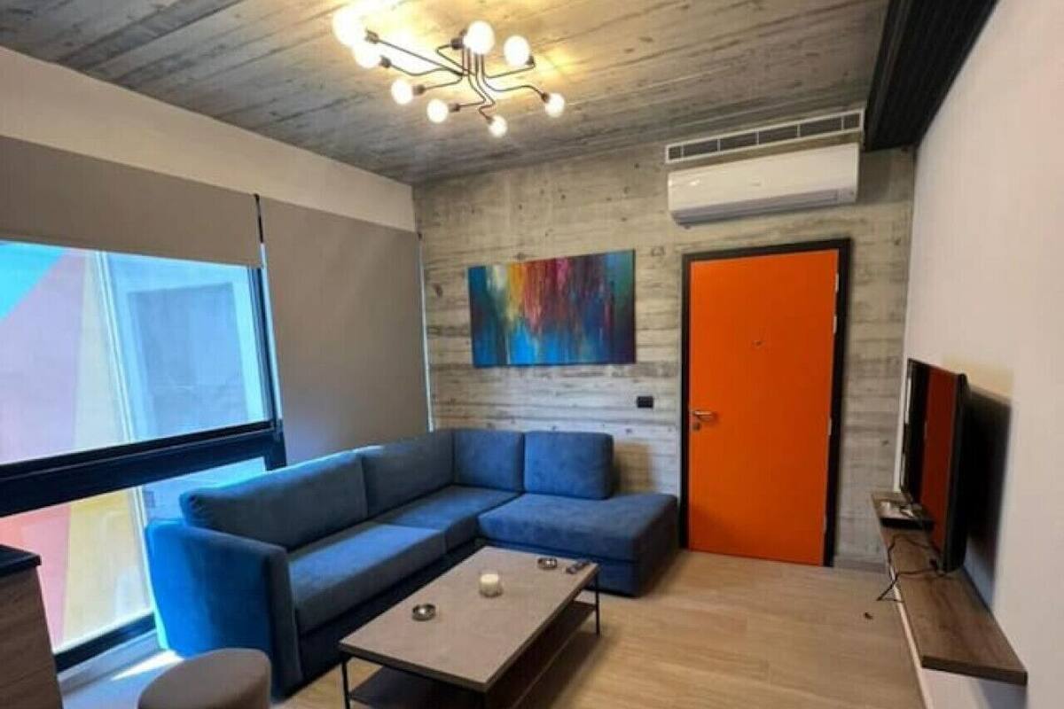 Una sala moderna con un sofá seccional azul, una pequeña mesa de centro y un ventanal grande.