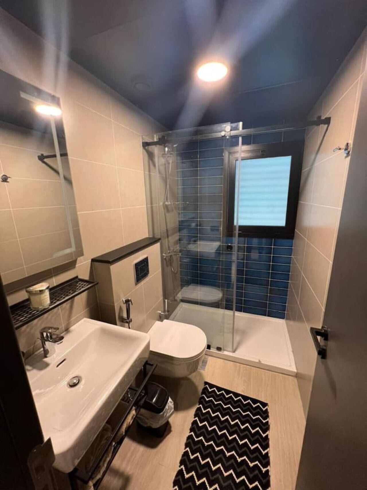 A modern bathroom with a glass-enclosed shower, a white sink, and a toilet.