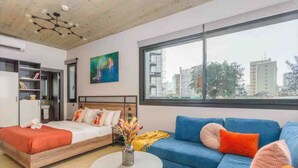A modern hotel room with a bed, a sofa, a round table, and a large window offering a city view. - Amine Apart-Hotel by Stayinn (Beirut)