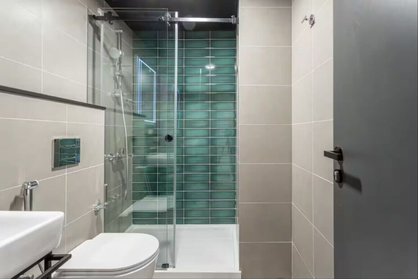 A modern bathroom with a glass shower enclosure, a white toilet, and a sink.