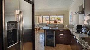 A modern kitchen with a built-in refrigerator, a central island, and a dining area with a sofa and table.