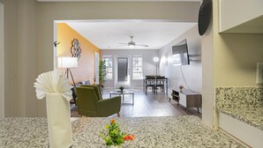 A modern kitchen with granite countertops, a dining area with a table and chairs, and a living room with a sofa and a plant. - Chic 2-bedroom apartment with WiFi, AC in marvelous Austin (Austin)