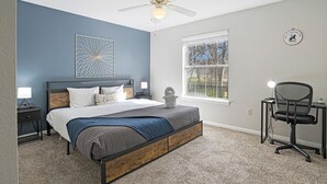 A bedroom with a bed, a desk, a chair, a ceiling fan, a window, and a decorative wall piece. - Chic 2-bedroom apartment with WiFi, AC in marvelous Austin (Austin)