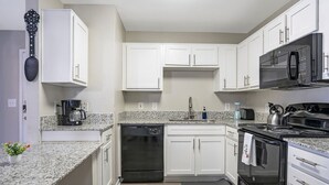 A modern kitchen with white cabinets, a dishwasher, a stove, a microwave, and a coffee maker. - Chic 2-bedroom apartment with WiFi, AC in marvelous Austin (Austin)