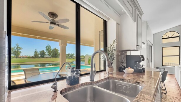 A kitchen with a large sink, a coffee maker, and a view of a golf course and pool. - 4BR w lake view, hot tub, ping pong (Chandler)