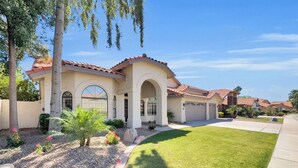 A residential house with a tiled roof, arched windows, and a well-maintained lawn. - 4BR w lake view, hot tub, ping pong (Chandler)