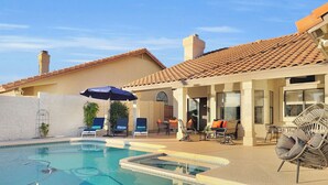 A swimming pool with lounge chairs and umbrellas, a covered patio area, and a building with a tiled roof. - 4BR w lake view, hot tub, ping pong (Chandler)