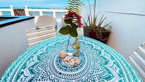A round table with a patterned tablecloth, a potted plant, and a vase with flowers.