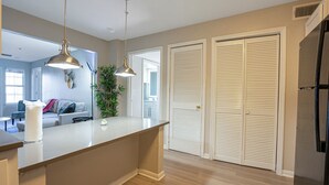 A modern kitchen with a central island, pendant lights, a refrigerator, and a dining area with a sofa and a plant. - Charming 2-bedroom apartment with WiFi, AC in pleasant Austin (Austin)