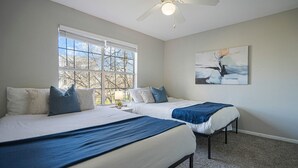 A bedroom with two beds, a ceiling fan, a window with blinds, and a painting on the wall. - Charming 2-bedroom apartment with WiFi, AC in pleasant Austin (Austin)