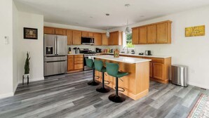 Eine moderne Küche mit Holzausstattung, Edelstahlgeräten und einer zentralen Kochinsel mit Barhocker.