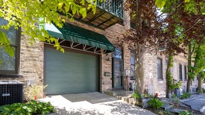 A residential building with a green awning, brick facade, and a garage door. - Downtown Grand Haven | Channel Views + Loft (Grand Haven)