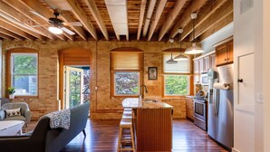 A spacious kitchen with wooden beams, a bar area, and a seating area with a couch and table. - Downtown Grand Haven | Channel Views + Loft (Grand Haven)