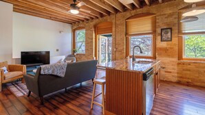 A living room with a sofa, TV, and wooden flooring. - Downtown Grand Haven | Channel Views + Loft (Grand Haven)