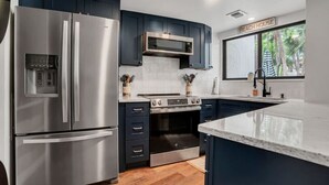A modern kitchen with stainless steel appliances, dark cabinetry, and a large island.