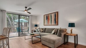 A living room with a sofa, coffee table, two lamps, and a ceiling fan.
