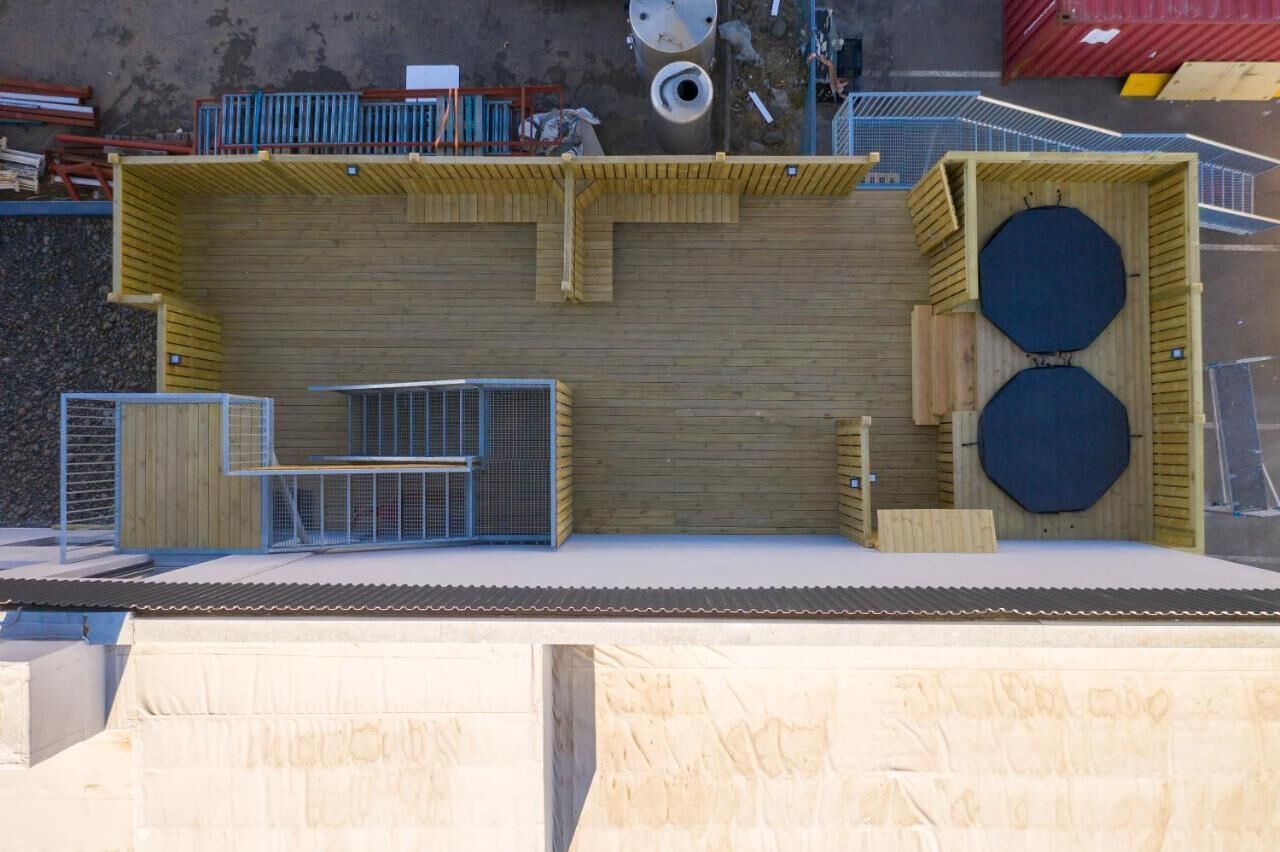 A construction site with a wooden structure, metal fencing, and construction materials.