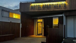 L'ingresso di un hotel con facciata in legno e una insegna con la scritta 'HOTEL APARTMENTS'.