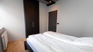 Una camera da letto con un letto, un armadio scuro, una porta e un termosifone.