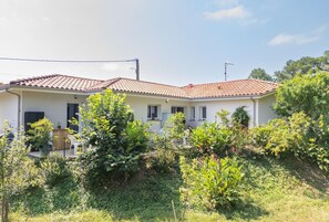 A two-story house with a tiled roof, a front porch, and a garden with various plants. - Relaxation for Two - SAINT MARTIN DE SEIGNANX (Unknown)