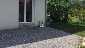 A building with a tiled roof, a door with glass panels, and a gravel driveway.