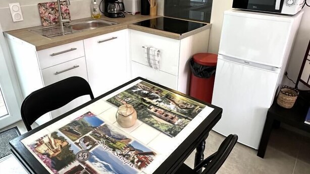 A compact kitchen with a dining table displaying a map, a microwave, and a coffee maker.