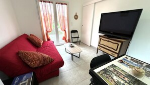 A compact living room with a red sofa, a television on a wooden cabinet, and a table with a map.