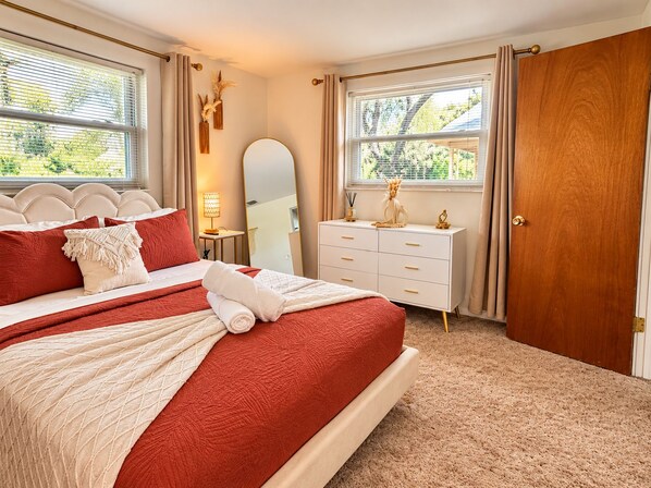 A bedroom with a bed, bedside tables, a dresser, and a door.