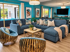 Ein modernes Wohnzimmer mit einem Ecksofa, zwei Sesseln, einem Couchtisch und einem Fernseher.