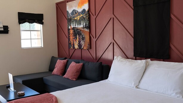 A modern hotel room with a large bed, a sofa, and a wall-mounted TV. - Tiny Oasis #1 - Hurricane, UT (Hurricane)