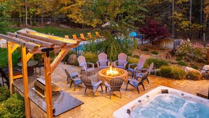 Un jardin avec un jacuzzi, un espace salon extérieur et un foyer.