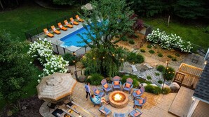 Un jardin avec une piscine, un espace salon extérieur, un jacuzzi et un foyer.