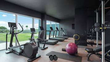 Un gimnasio moderno con cintas de correr, elípticas y pesas libres.