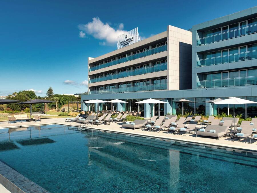 A modern hotel with a pool area, multiple floors, and a sign for Delta Hotels.