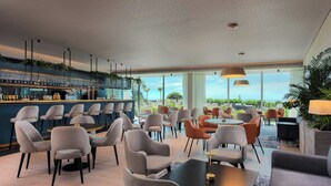 Ett modernt loungeområde med sittgrupper, en bar och stora fönster med utsikt.