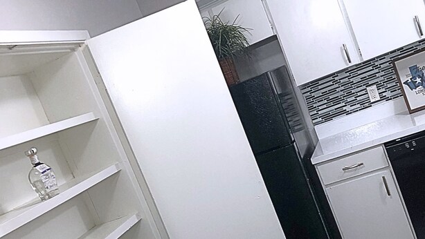 A kitchen with white cabinets, a black countertop, and a white marble sink.