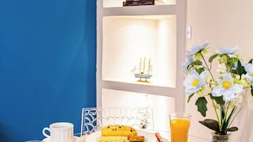 A breakfast setup with plates of food, a glass of orange juice, and a cup of coffee on a glass table.