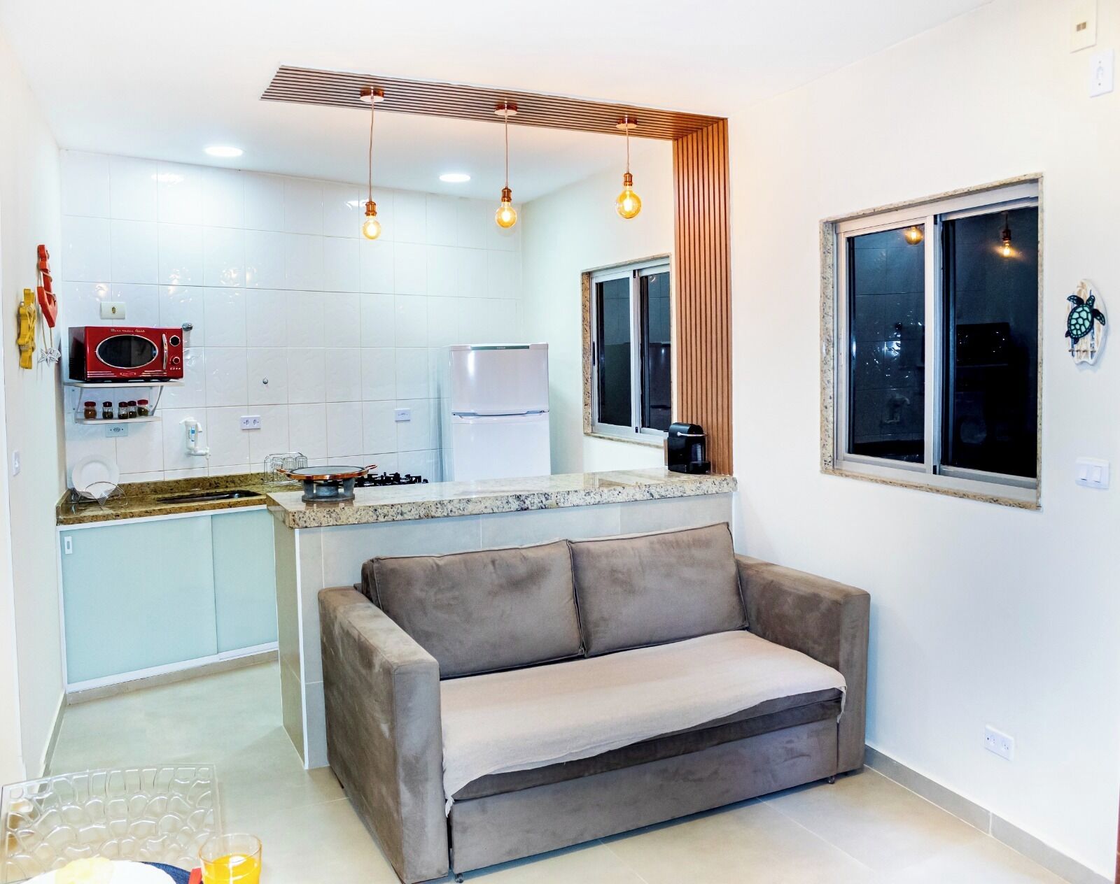 A compact living space with a kitchenette, a sofa, and a window with a view.