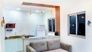 A compact living space with a kitchenette, a sofa, and a window with a view.