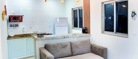 A compact living space with a kitchenette, a sofa, and a window with a view.