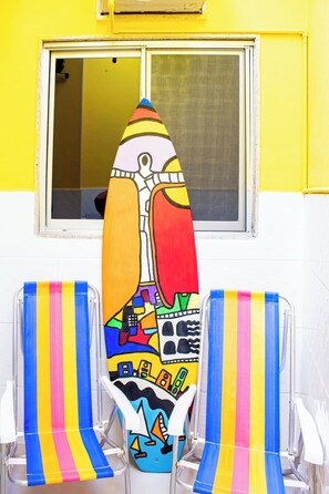 A room with a window, a colorful chair, and a chair with a vibrant, abstract design.