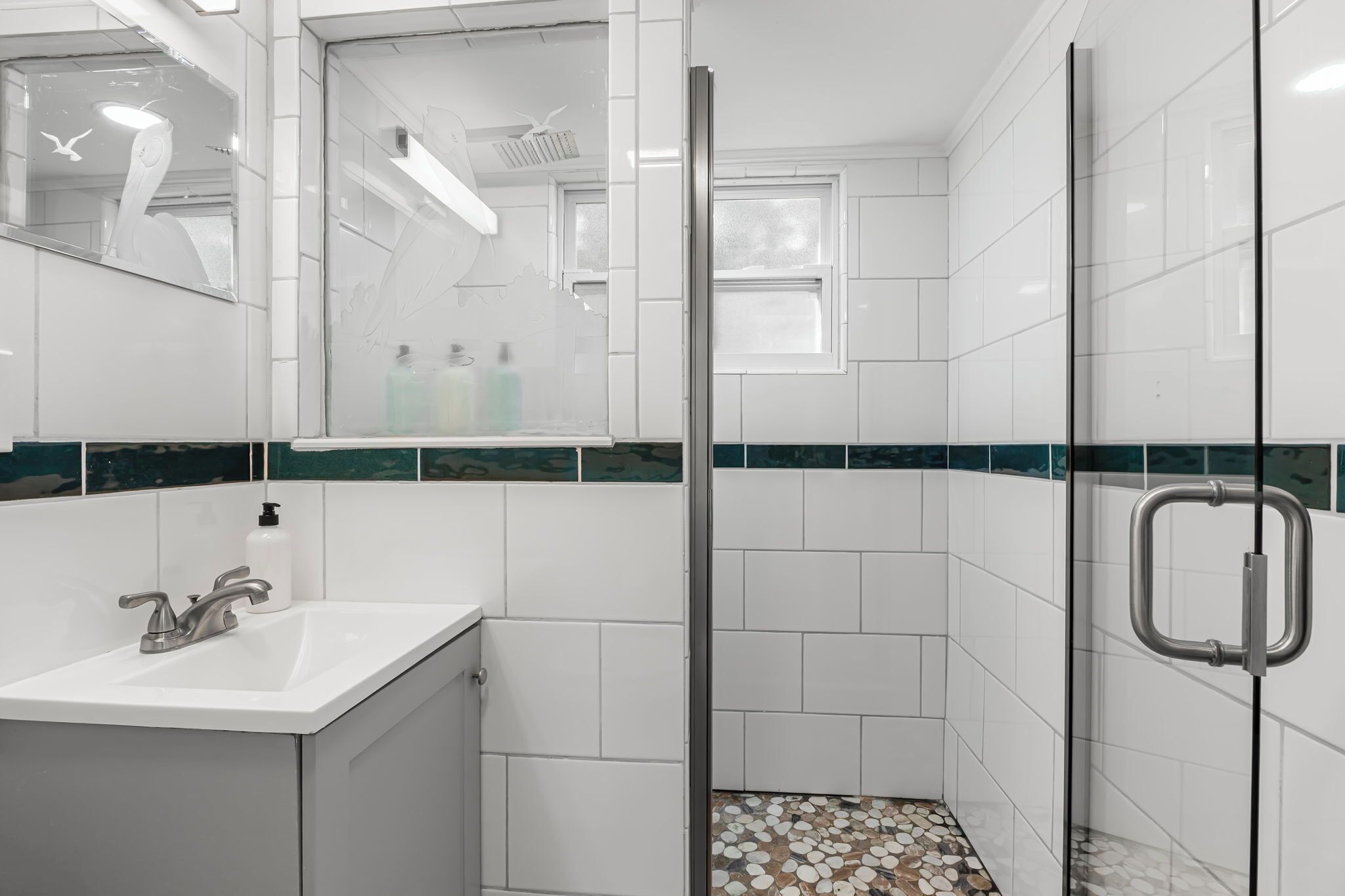 A bathroom with a white sink, mirror, and shower area.